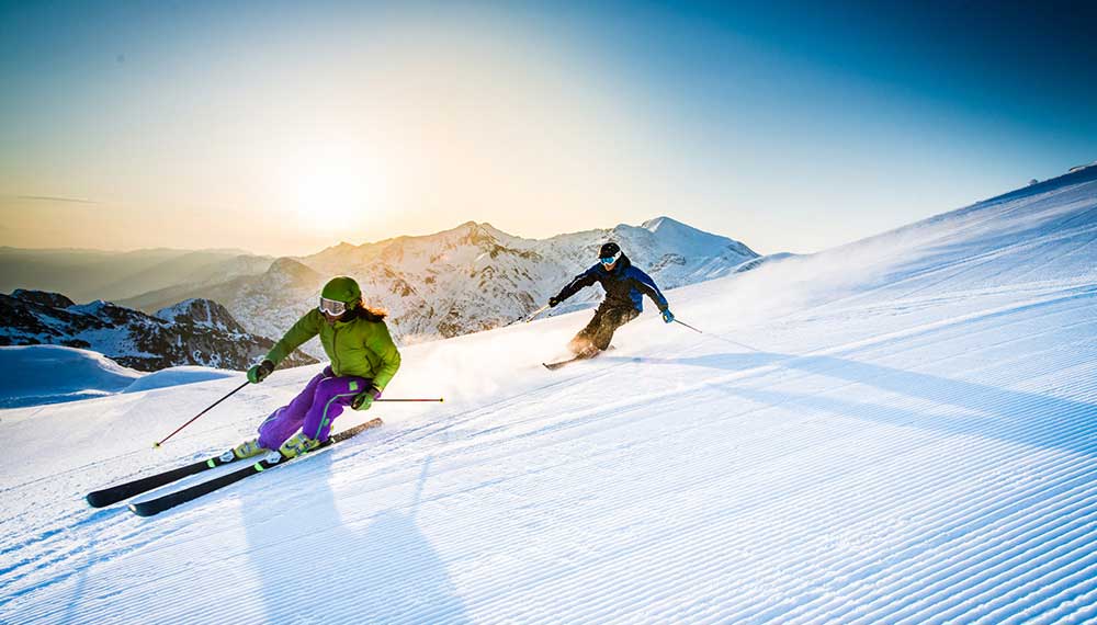 Two Skiiers Going Down A Mountain Slope